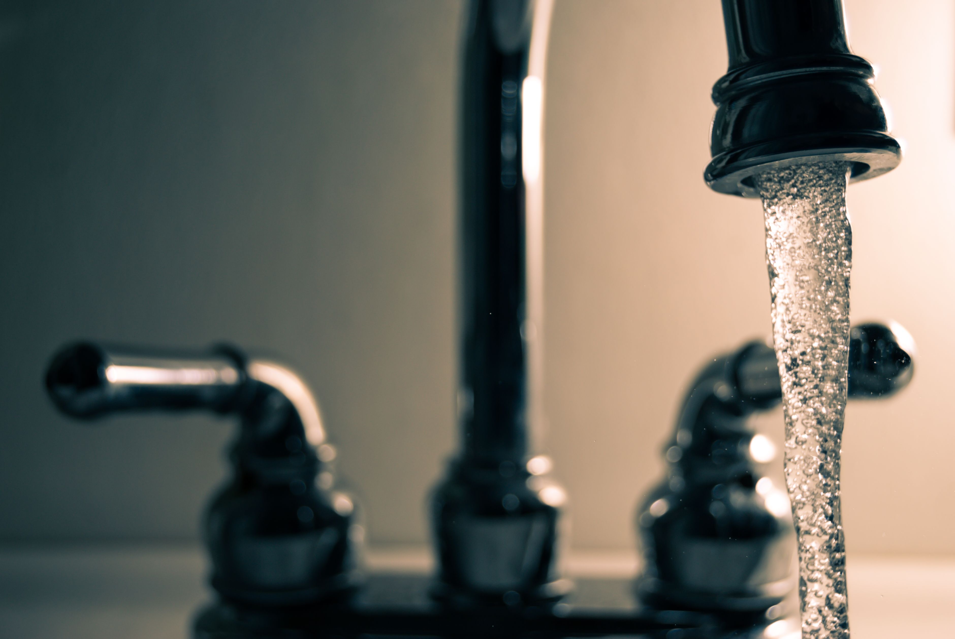 Zacht water stroomt uit een keukenkraan in een glas